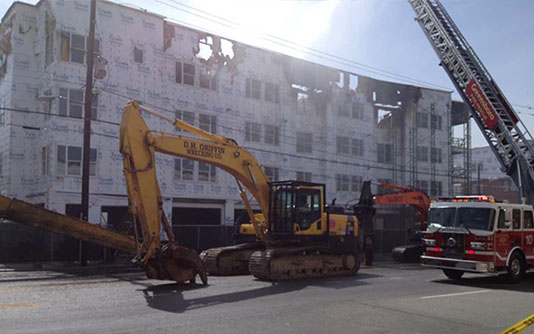 Bulldozer and firetruck in front of burned building